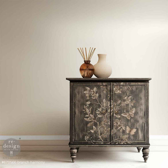 A small buffet cabinet painted with a black-wash style design features ReDesign with Prima's Branch Harmony rub-on furniture transfer on its 2 doors.