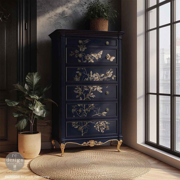 A vintage 6-drawer chest dresser is painted dark blue with gold details and features ReDesign with Prima's Branch Harmony rub-on furniture transfer on the drawers.