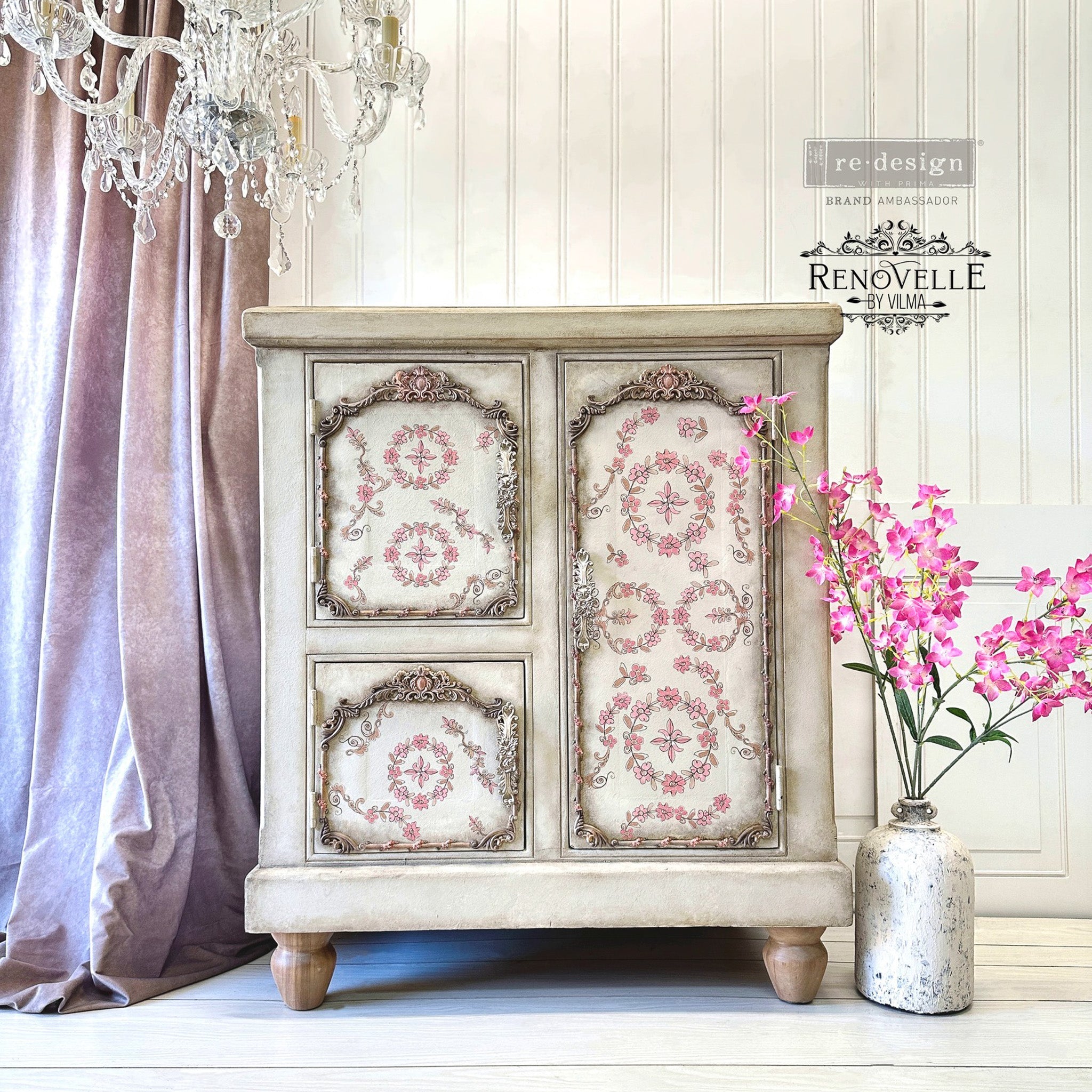 A vintage side table with storage refurbished by Renovelle by Vilma is painted antique white and features ReDesign with Prima's Annie Sloan Flower Garland rub-on transfer on the front of it.