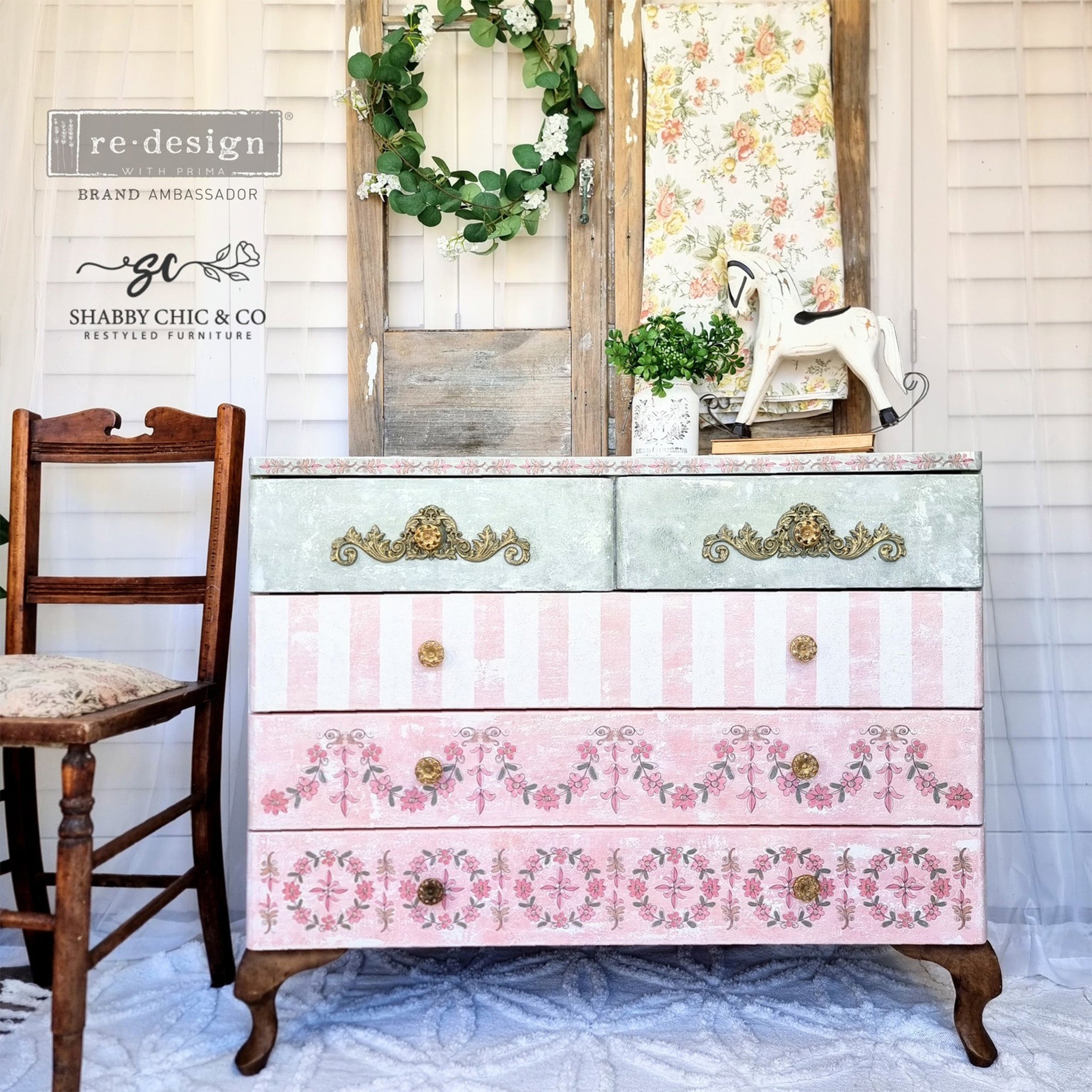 A 5-drawer dresser refurbished by Shabby Chic & Company is painted pastel green and pink and features ReDesign with Prima's Annie Sloan Floral Garland transfer on the 2 bottom drawers.