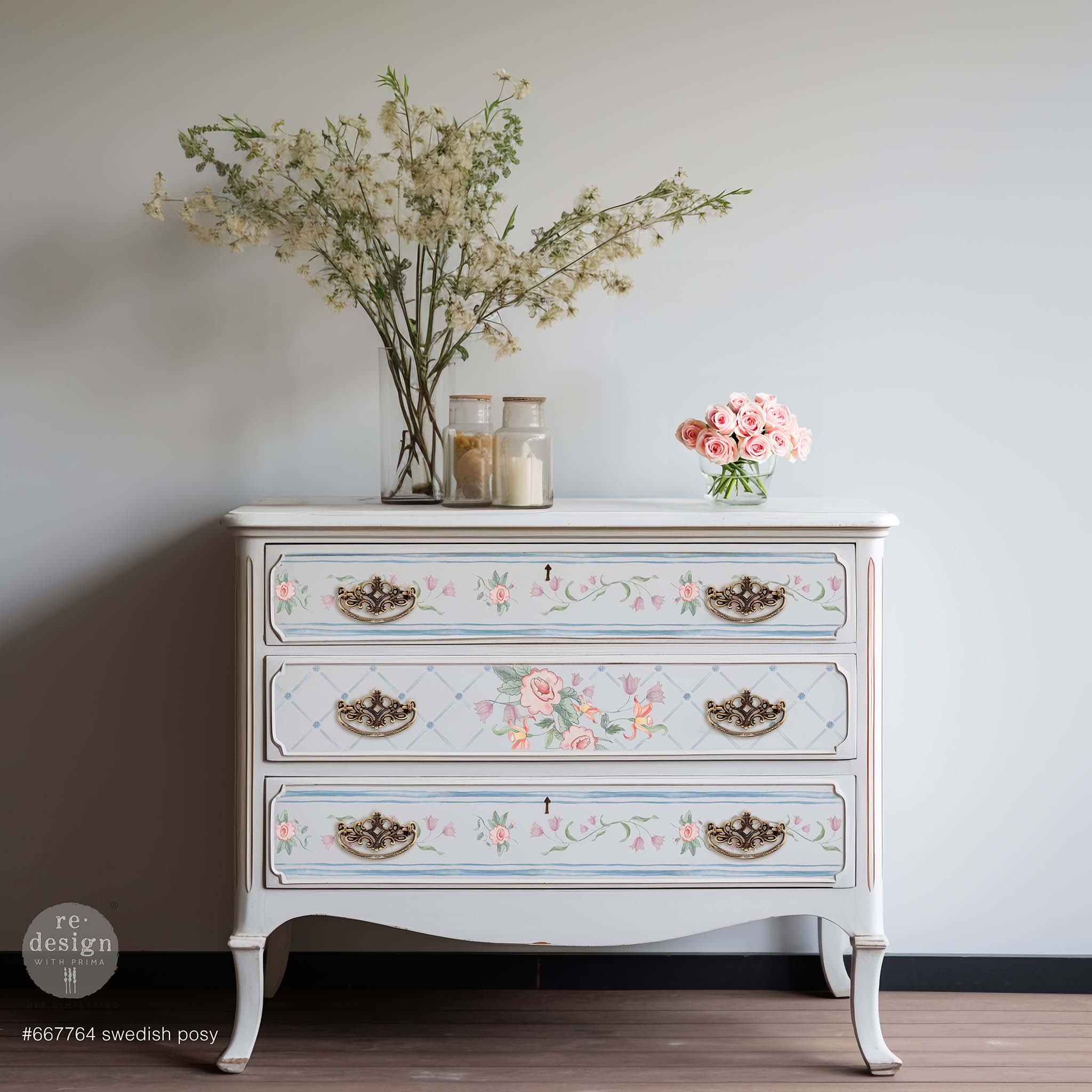 A vintage 3-drawer dresser is painted white and features ReDesign with Prima's Swedish Posy Transfer by Annie Sloan on its drawers.