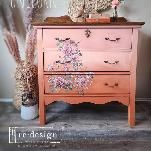 A vintage 3-drawer nightstand is painted an ombre of light to medium salmon pink and features ReDesign with Prima's Gentle Symphony rub-on transfer on the drawers.