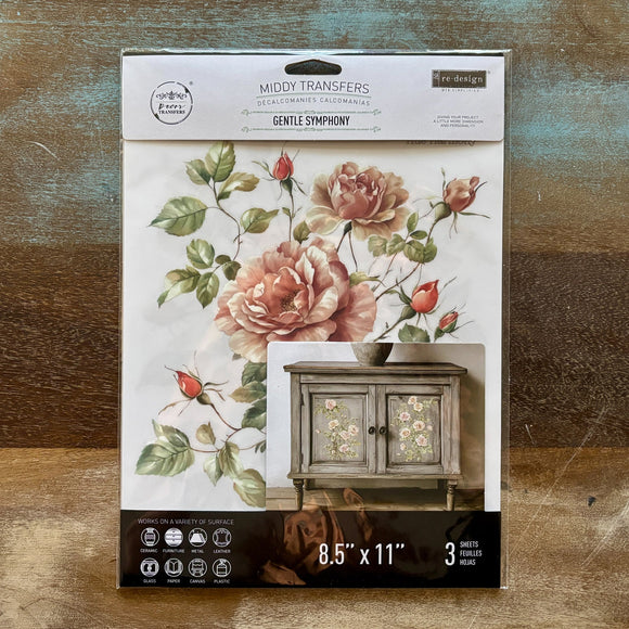 A package of ReDesign with Prima's Gentle Symphony small rub-on transfers is against a wood background.