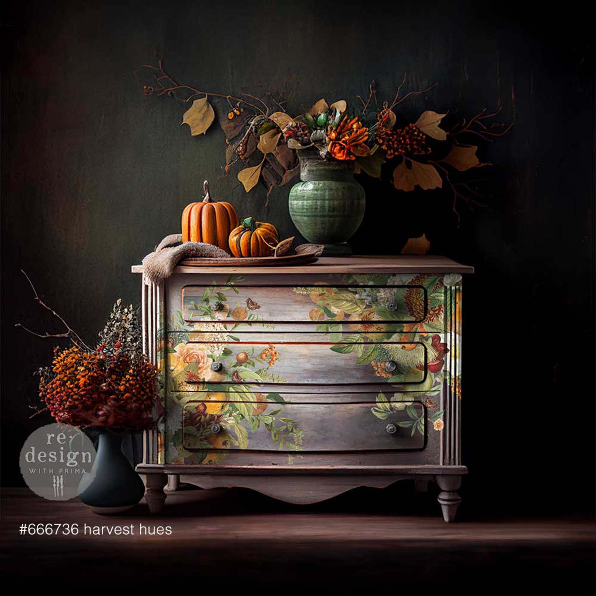 A vintage dresser is painted a blend of light grey and mauve and features ReDesign with Prima's Harvest Hues transfer on the front.
