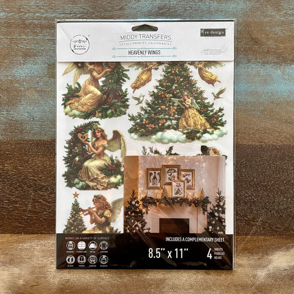 A package of ReDesign with Prima's Heavenly Wings middy rub-on transfers is against a wood background.
