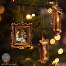 Decorative Christmas ornament with a gold frame on a lit Christmas tree.