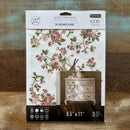A package of ReDesign with Prima's Kacha The Enchanted Grove small rub-on transfers is against a wood background.