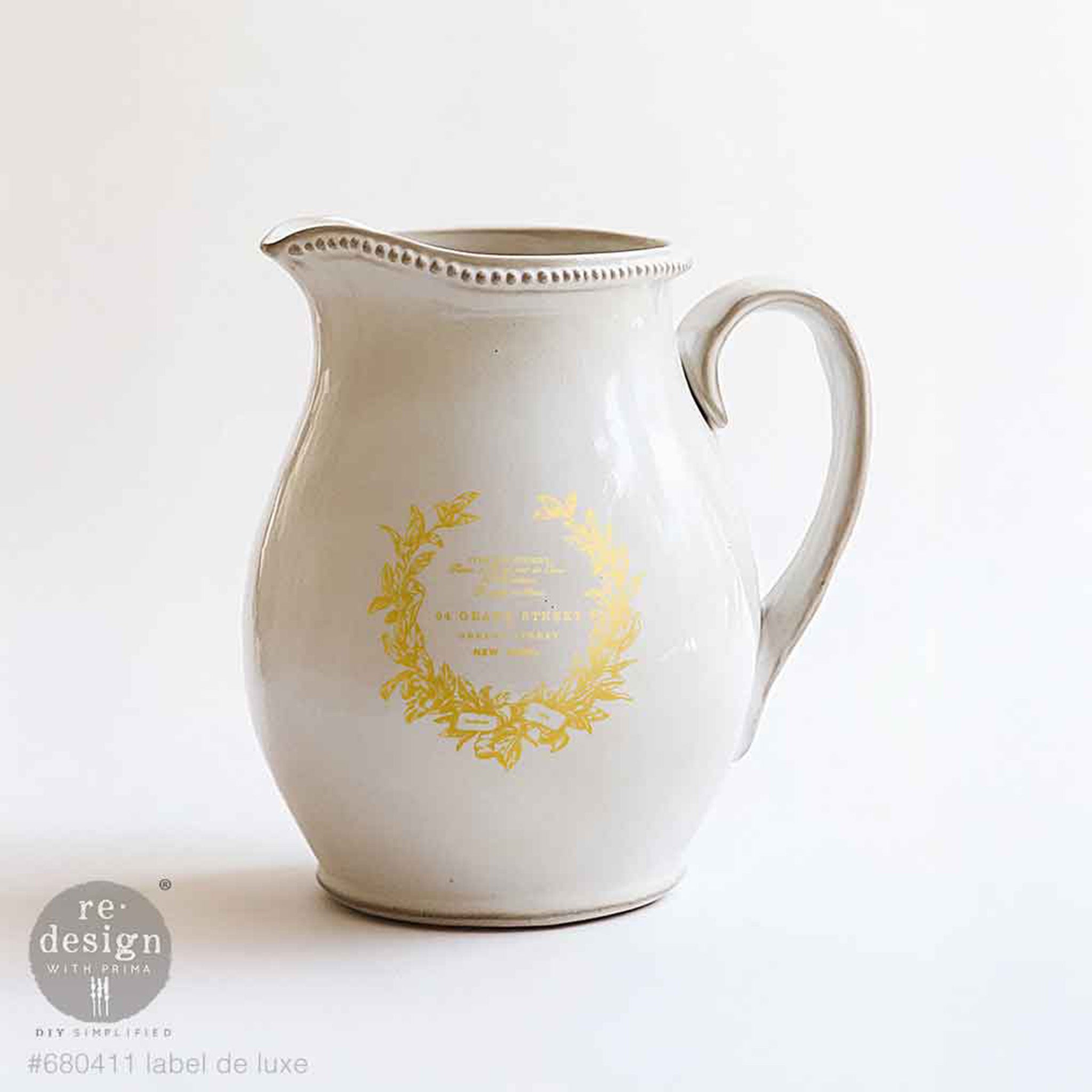 White ceramic pitcher with gold decorative elements on a white background, featuring the Redesign with Prima logo.