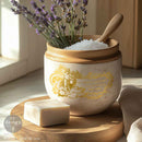 Decorative jar with gold design, lavender, and soap on a wooden surface.