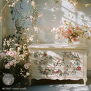 Decorative chest of drawers with floral and bird patterns, surrounded by flowers.