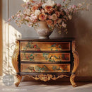 Decorative chest of drawers with floral design next to a vase of flowers on a neutral background