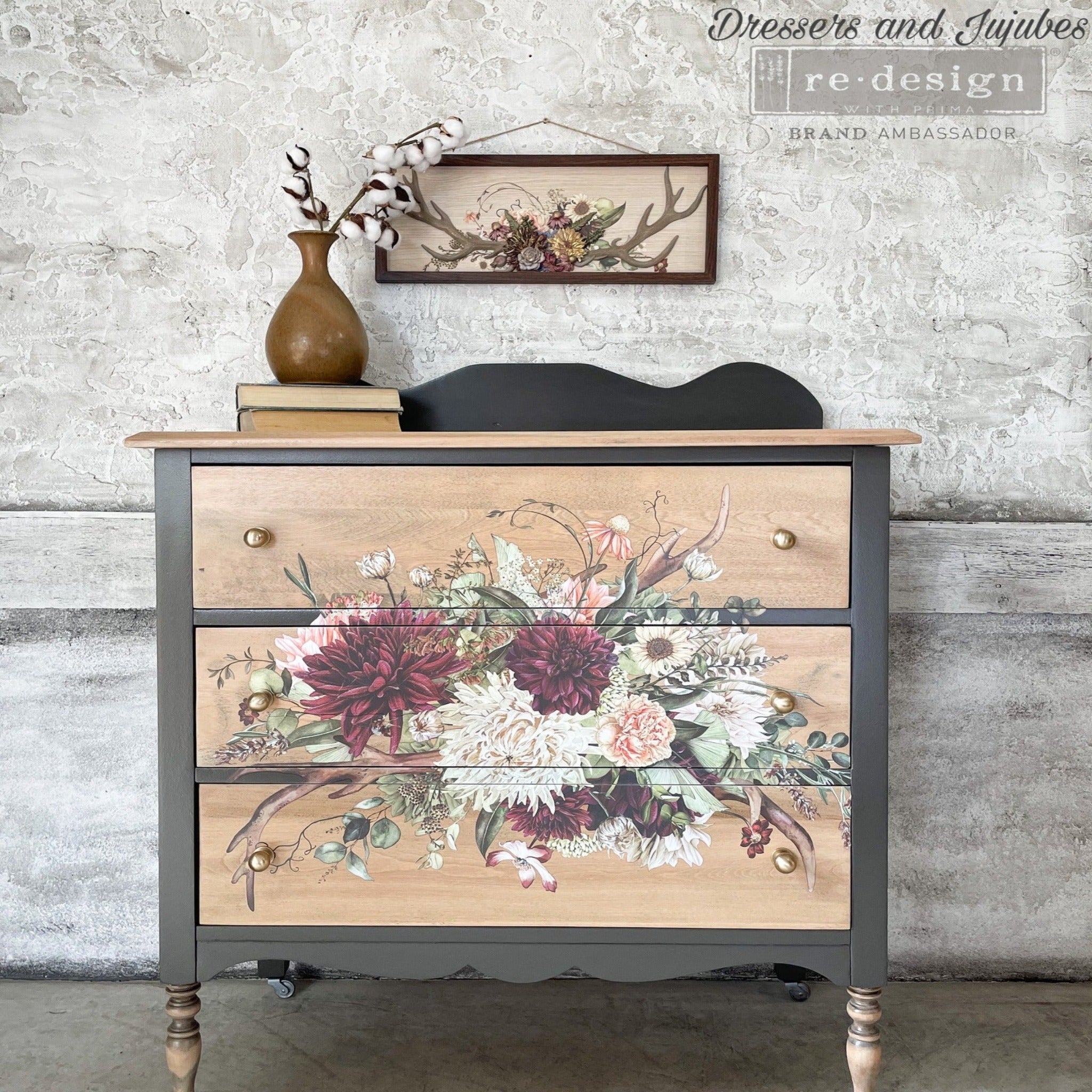 A vintage 3-drawer dresser refurbished by Dressers and Jujubes is painted grey with light natural wood drawers and features ReDesign with Prima's Rustic Charm furniture transfer  on the front.