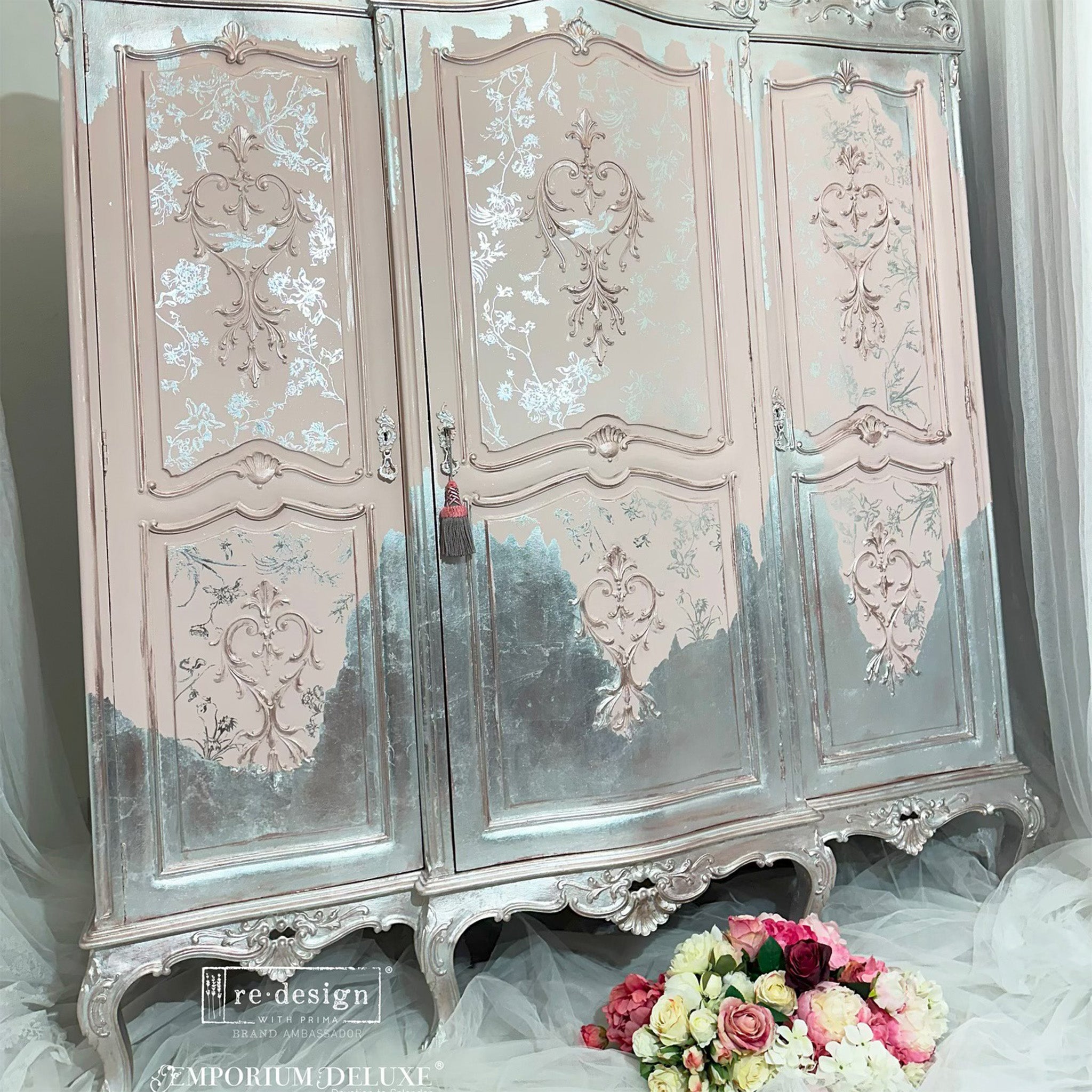 A large vintage armoire refurbished by Emporium Deluxe is painted soft pale pink and silver gold foil and features ReDesign with Prima's Kacha Silver Bird transfer on the pink.