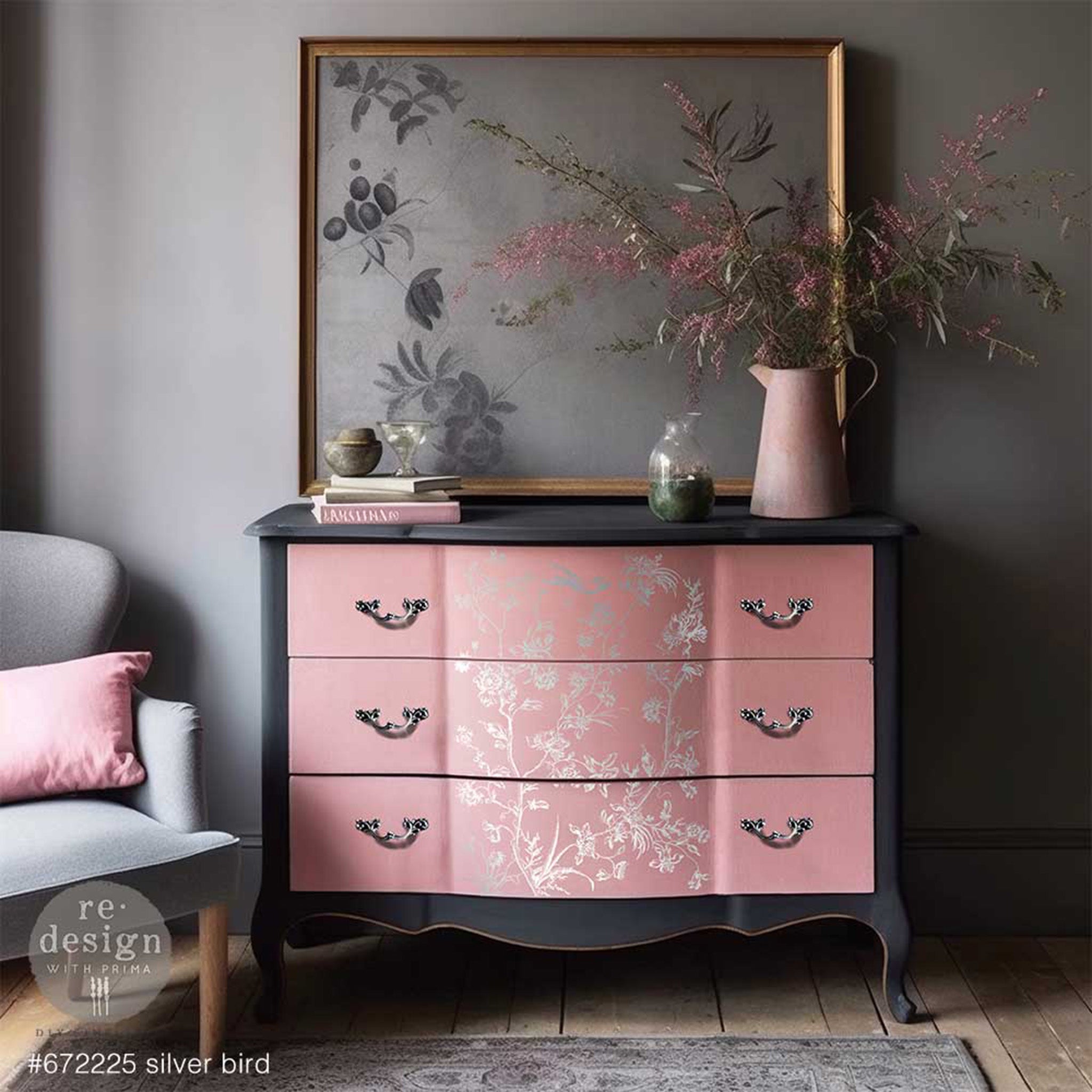 A vintage 3-drawer dresser is painted pink and dark gray that features ReDesign with Prima's Kacha Silver Bird Silver Foil transfer on the front.