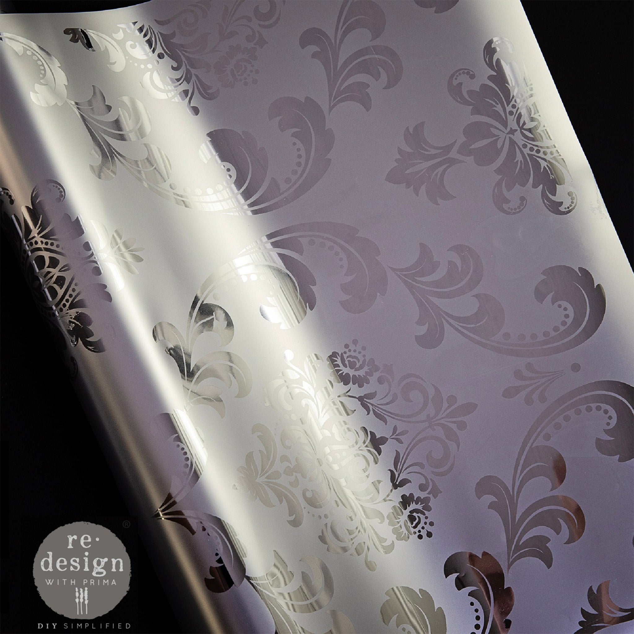 A super close-up of ReDesign with Prima's Kacha House of Damask Silver foil transfer is shown on a white wood crown molding piece.