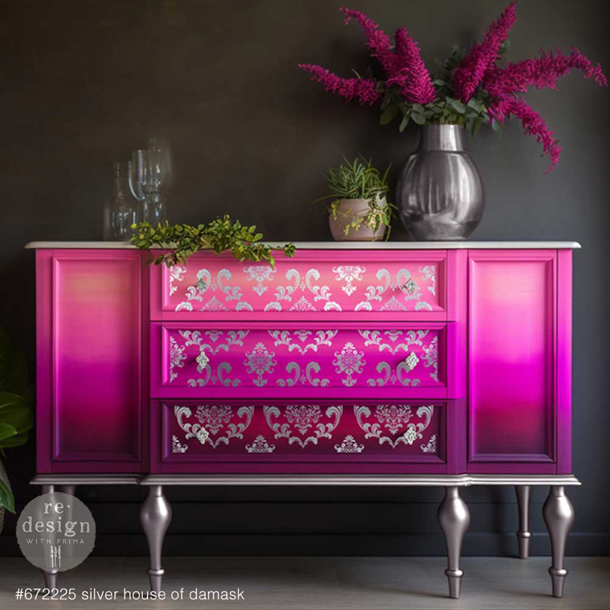 A vintage large dresser is painted an ombre blend of light and dark pinks and features ReDesign with Prima's Kacha Silver Foil House of Damask transfer on its 3 center drawers.