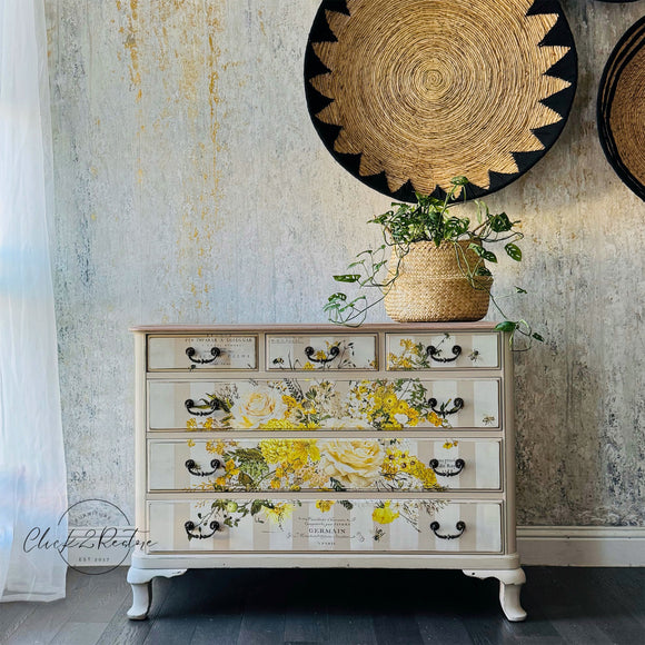 A vintage 6-drawer dresser is painted light beige with soft white stripes and features ReDesign with Prima's Sunlit Serenade rub-on furniture transfer on the front.