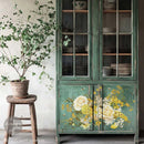 A hutch cabinet painted a muted green features ReDesign with Prima's Sunlit Serenade Transfer for large furniture on the bottom 2 doors.