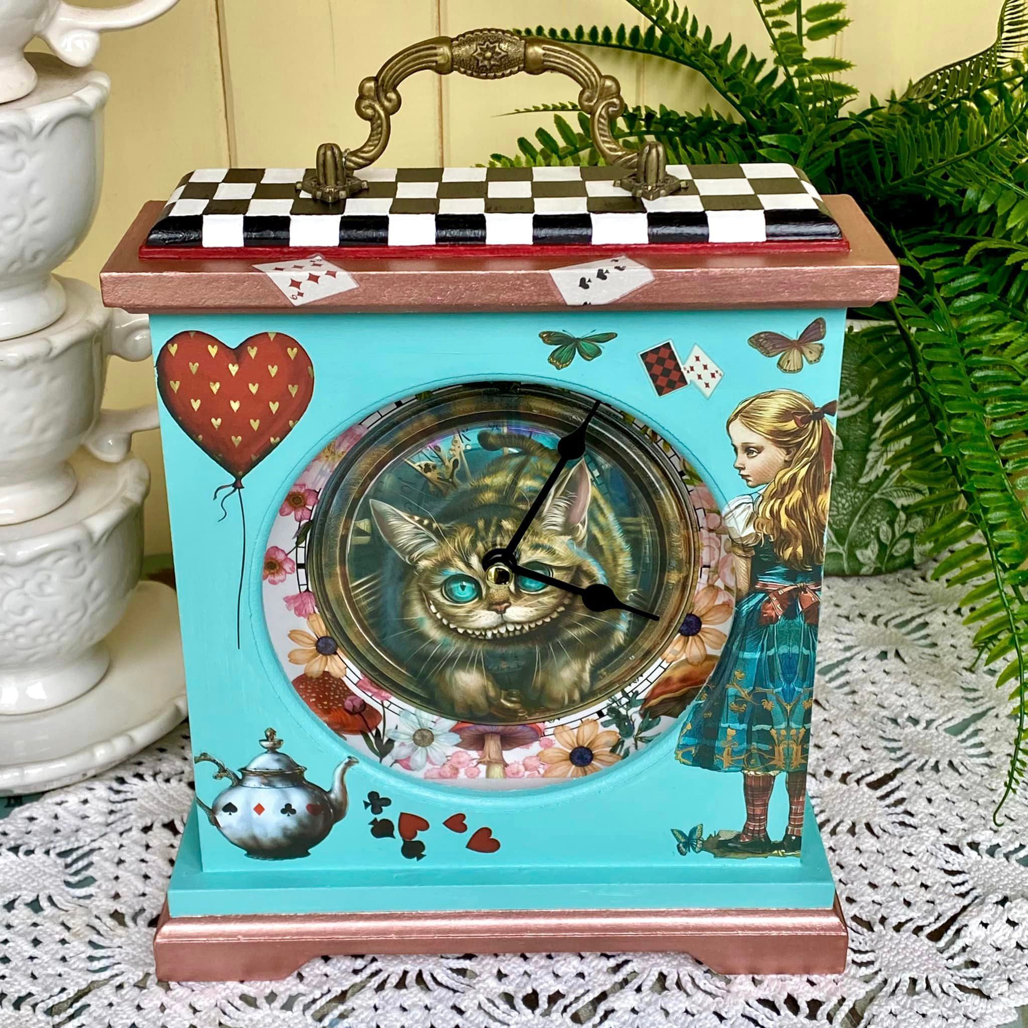 A small vintage table clock is painted light sky blue and features ReDesign with Prima's Whimsical Realm small rub-on transfers on it.