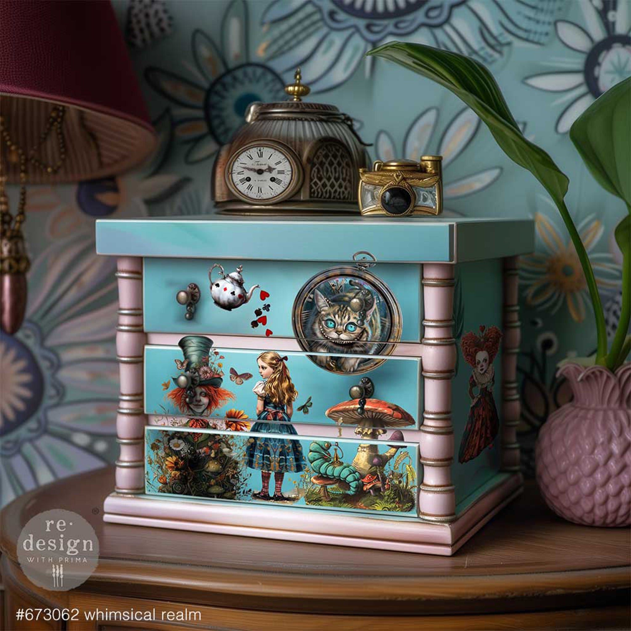 A small jewelry box with 3 drawers is painted pale blue and soft pink and features ReDesign with Prima's Whimsical Realm small transfers on it.