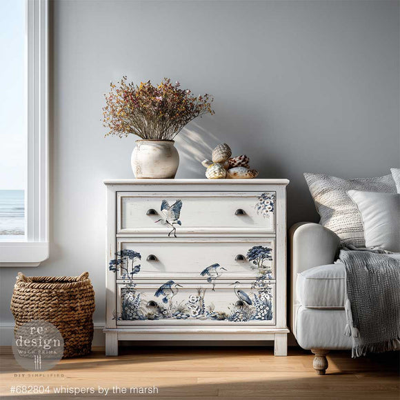 Decorative chest of drawers with nature-themed design in a room with a couch and window.