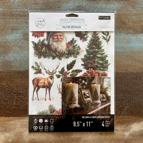 A package of ReDesign with Prima's Yuletide Nostalgia middy rub-on transfers are against a wood background.