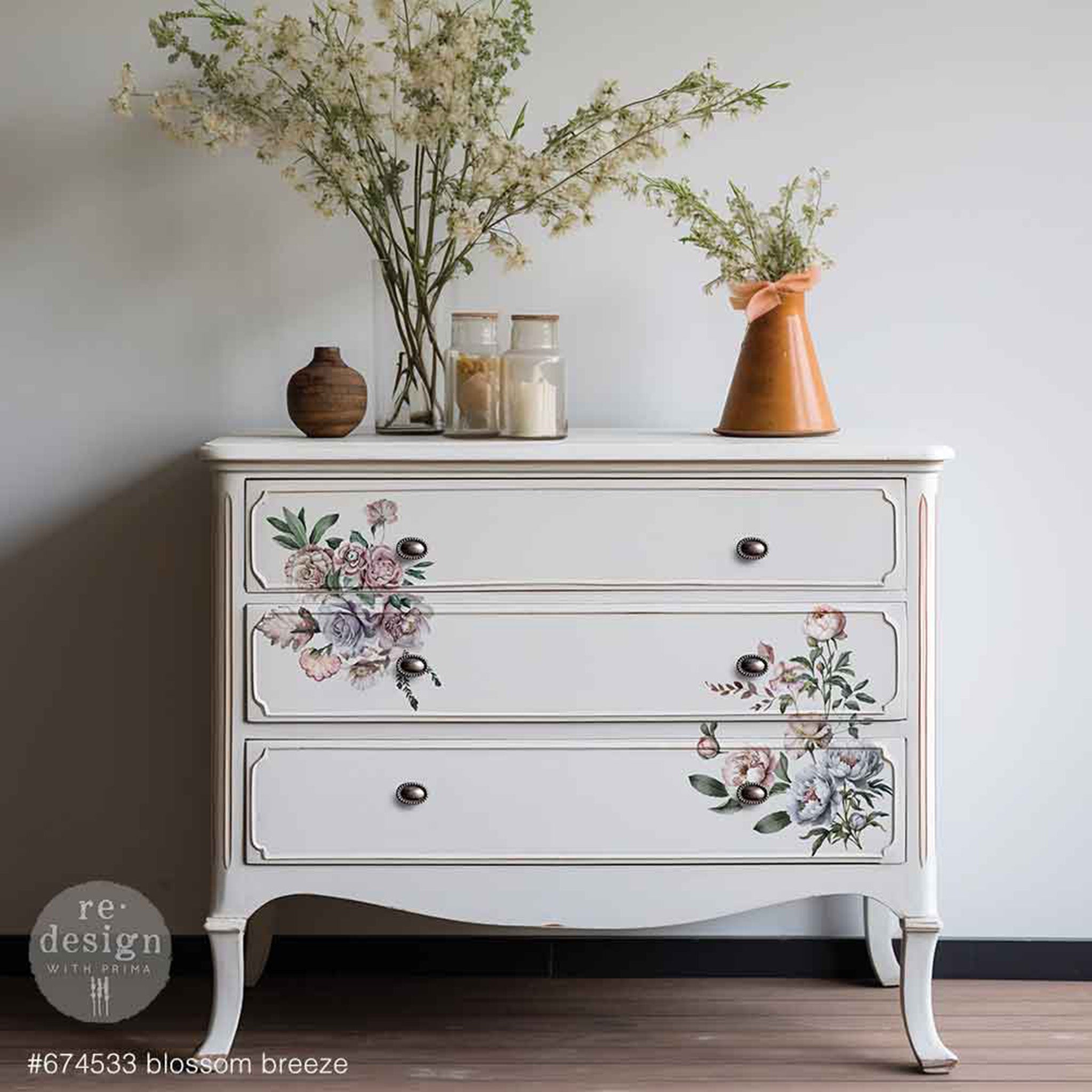 A 3-drawer dresser is painted white and features 2 of ReDesign with Prima's Blossom Breeze small rub-on transfers on the drawers.