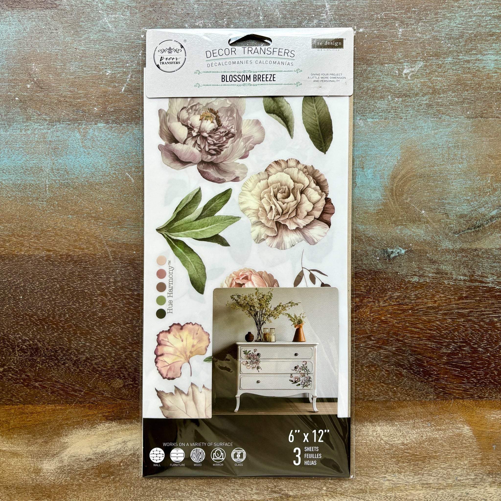 A package of ReDesign with Prima's Blossom Breeze small rub-on transfers is against a wood background.