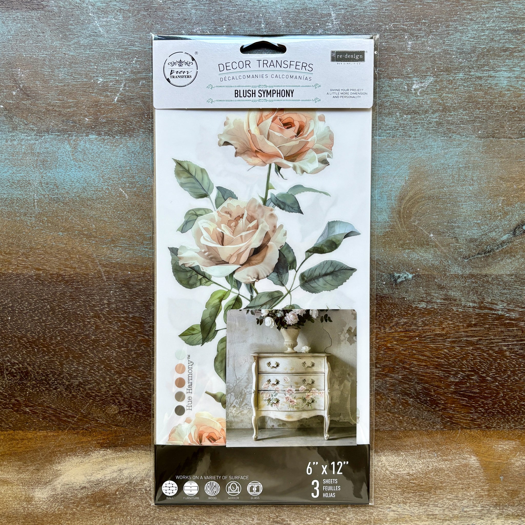 A package of ReDesign with Prima's Blush Symphony small rub-on transfers is against a wood background.