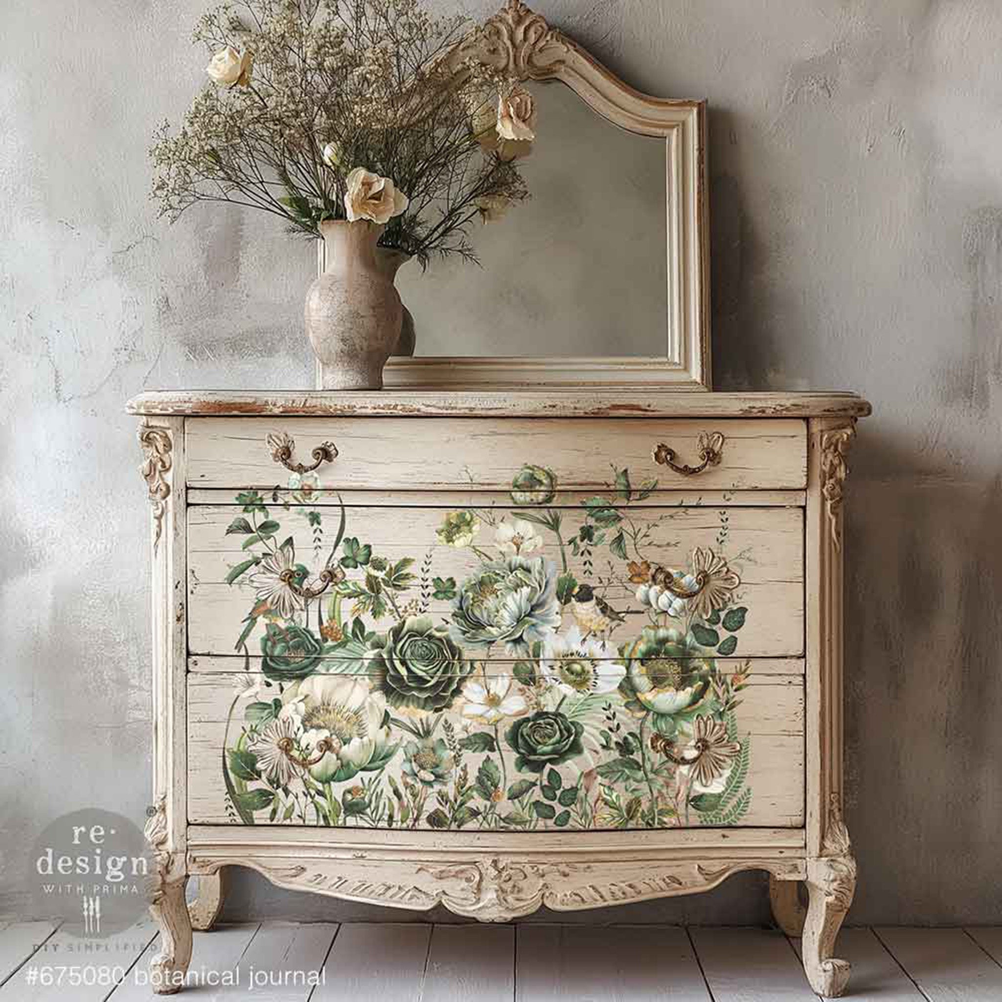 A weathered vintage dresser is painted light beige and features ReDesign with Prima's Botanical Journal rub-on transfers on the drawers.