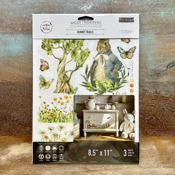 A package of ReDesign with Prima's Bunny Trails small rub-on transfers is against a wood background.