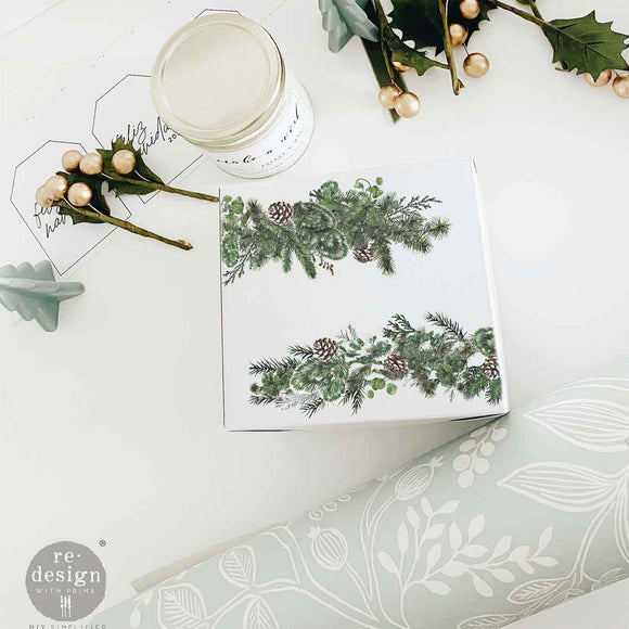 A white square coaster features pine sprig designs from ReDesign with Prima's Gilded Elegance middy rub-on transfers.