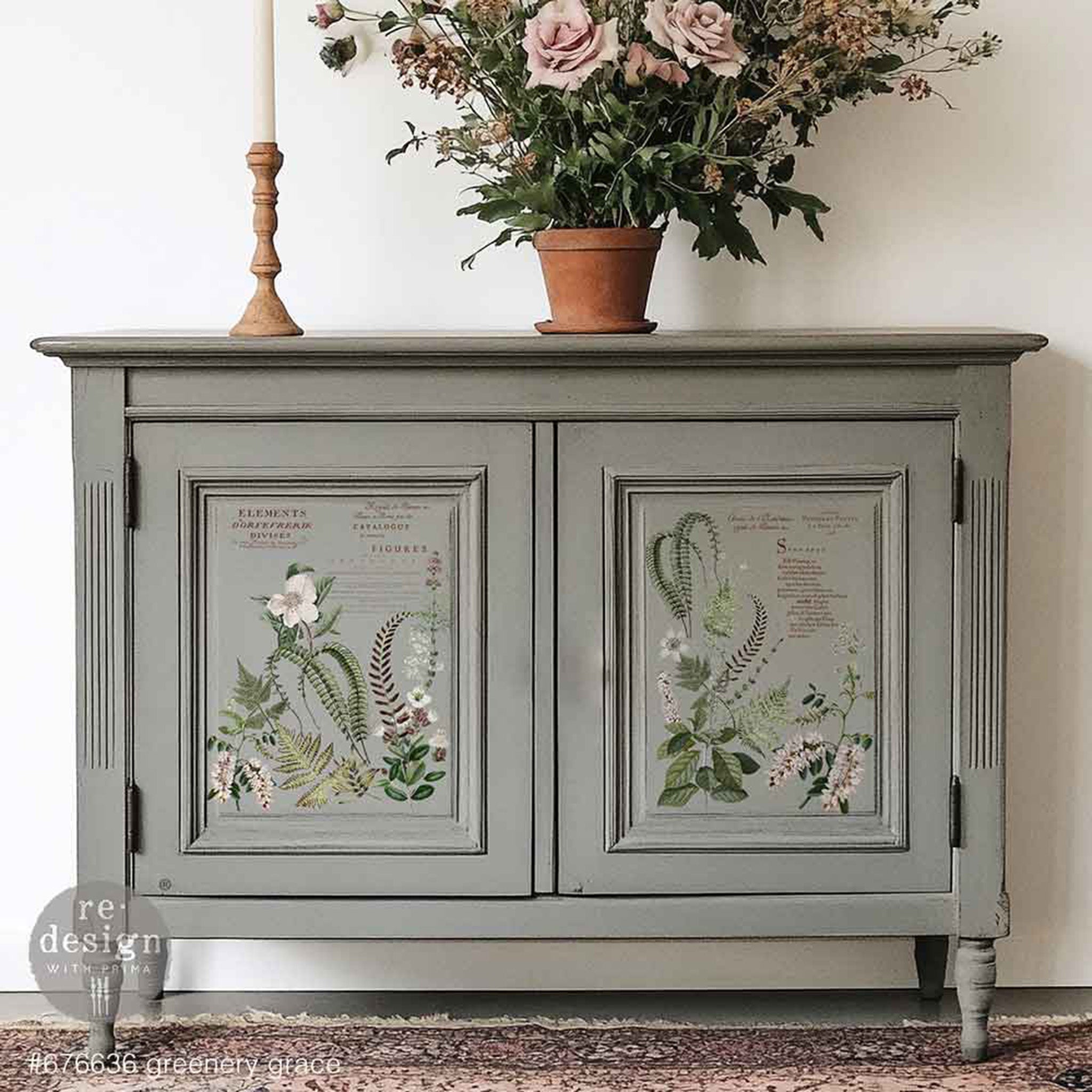 A small buffet cabinet is painted a warm grey and features ReDesign with Prima's Greenery Grace small rub-on transfers on its 2 door inlays.