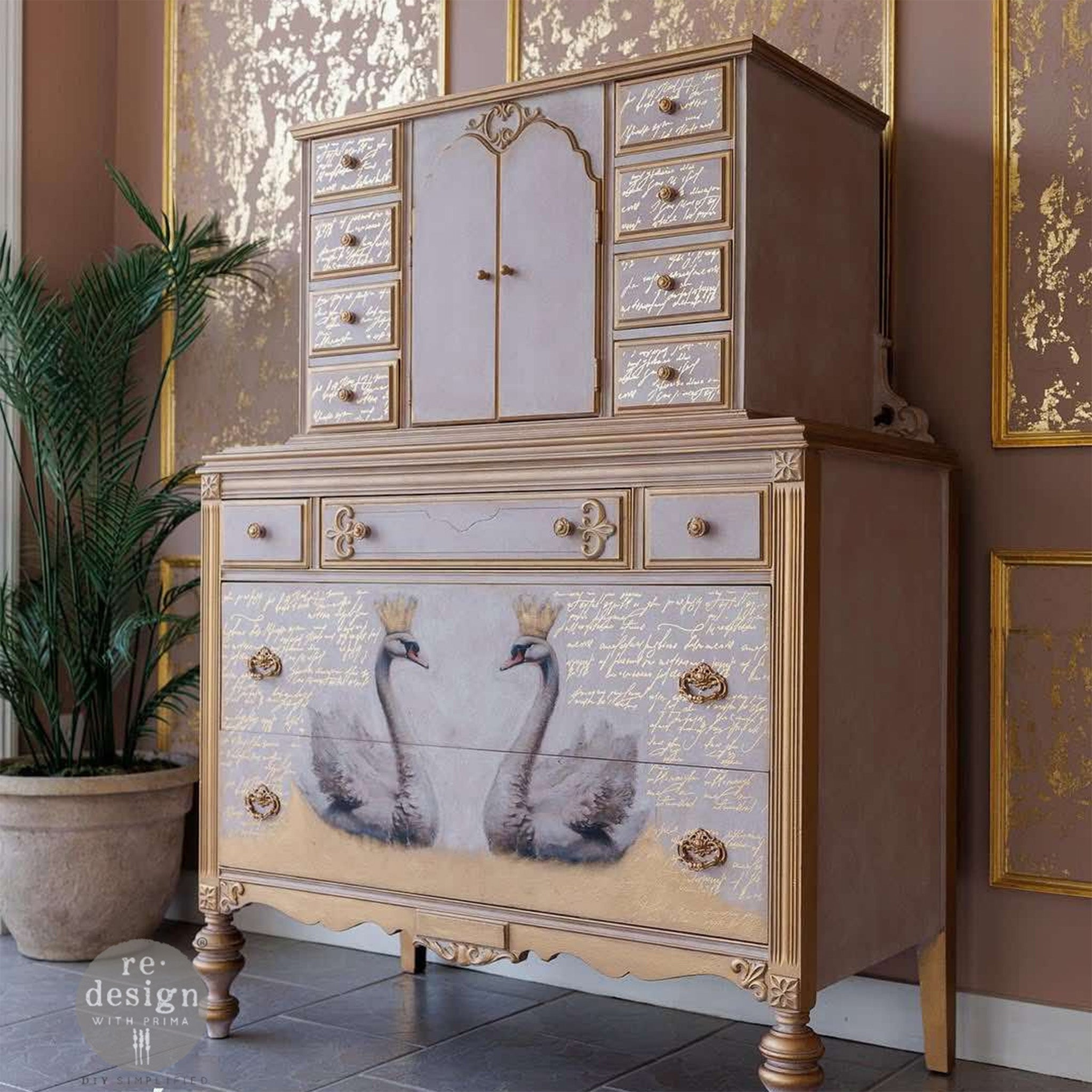 A vintage large lingerie dresser is painted pale pink with gold trim and features ReDesign with Prima's Kacha Shimmering Script gold foil rub-on transfer on its drawers.