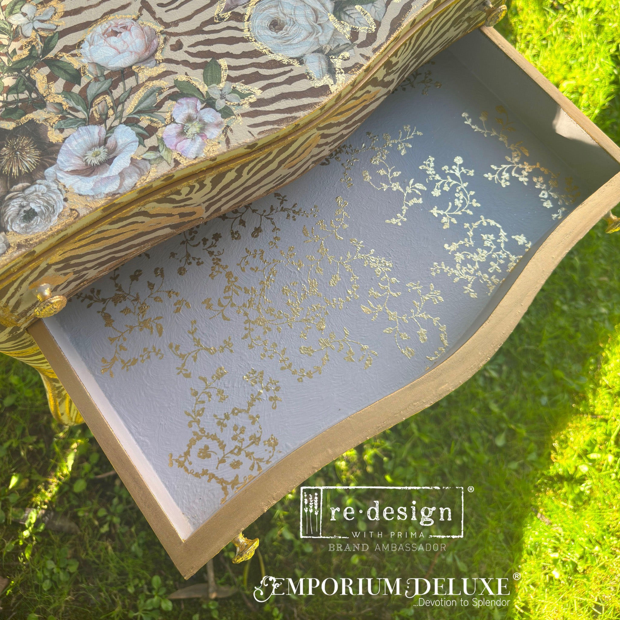 A top view of a vintage nightstand refurbished by Emporium Deluxe shows an open drawer that features ReDesign with Prima's Kacha Vineyard Elegance gold foil rub-on transfer inside.