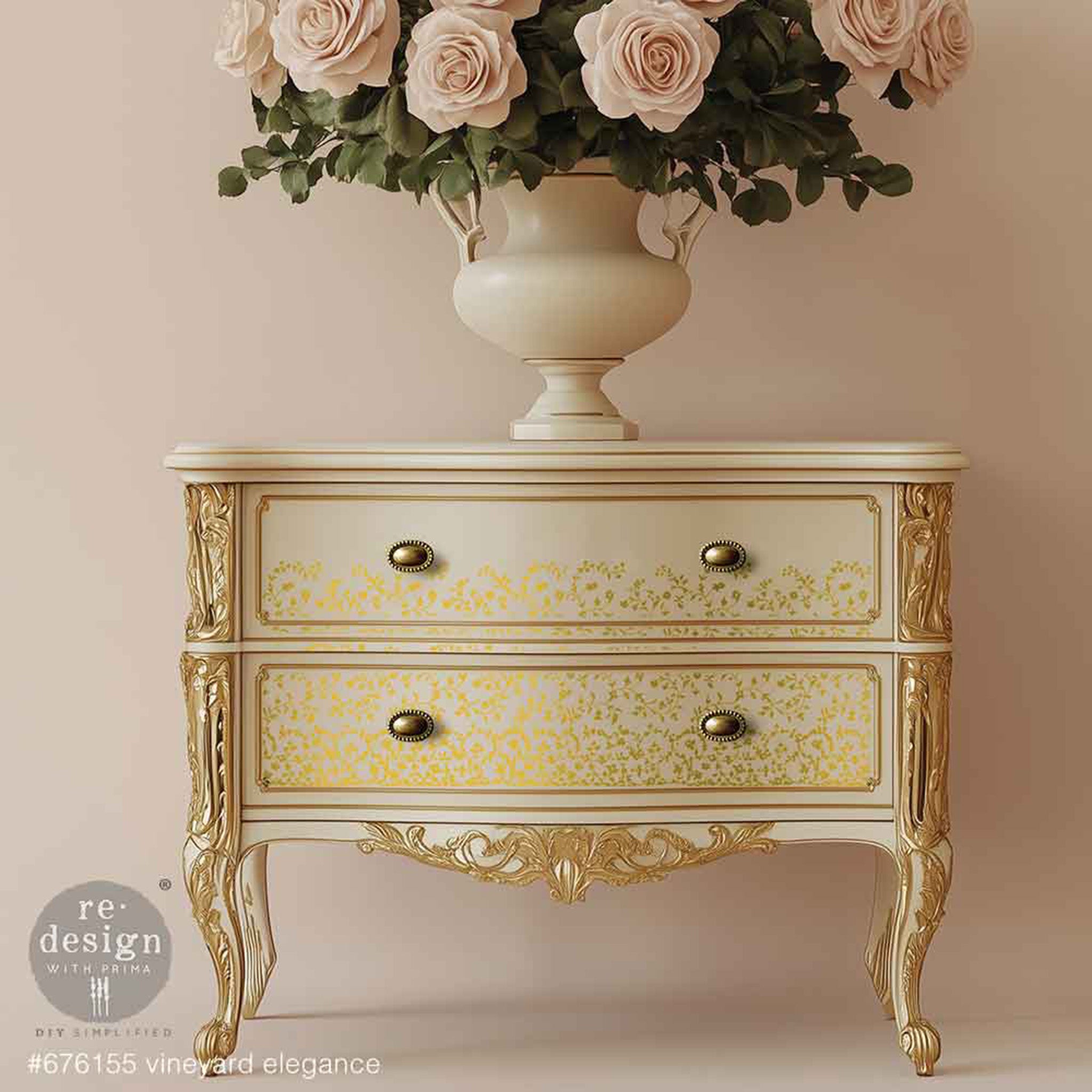 A vintage 2-drawer nightstand is painted champagne gold with gold accents and features ReDesign with Prima's Kacha Vineyard Elegance Gold Foil small rub-on transfers on the drawers.