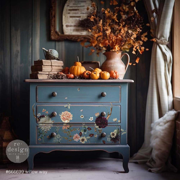 A vintage small 3-drawer dresser is painted a country blue and features ReDesign with Prima's Willow Way small transfer on its drawers.