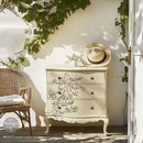 A small vintage 3-drawer dresser is painted off-white and features ReDesign with Prima's Quiet Contemplation middy rub-on transfers on the drawers.