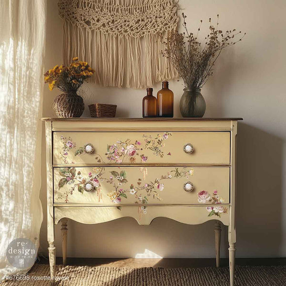 A vintage 2-drawer dresser with long legs is painted pale yellow and features ReDesign with Prima's Rosette Royale middy rub-on transfers on the drawers.