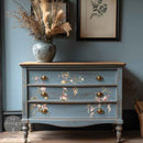 A vintage 3-drawer dresser is painted a soft blue and features ReDesign with Prima's Rosette Royale middy rub-on transfers on the drawers.