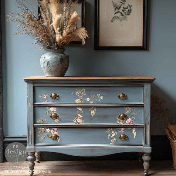 A vintage 3-drawer dresser is painted a soft blue and features ReDesign with Prima's Rosette Royale middy rub-on transfers on the drawers.