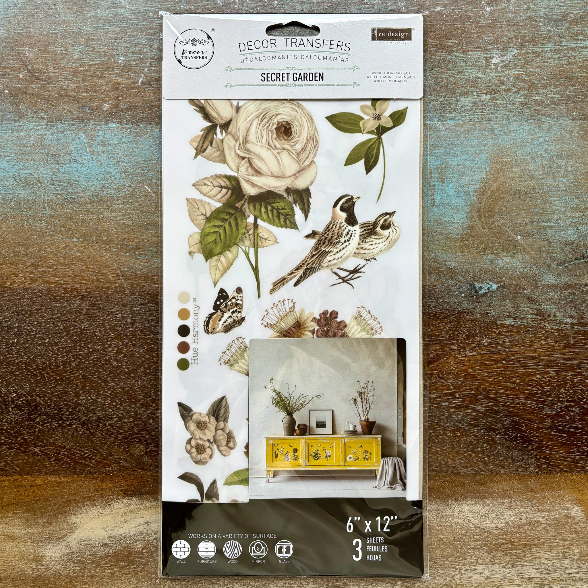 A package of ReDesign with Prima's Secret Garden small rub-on transfers is against a wood background.