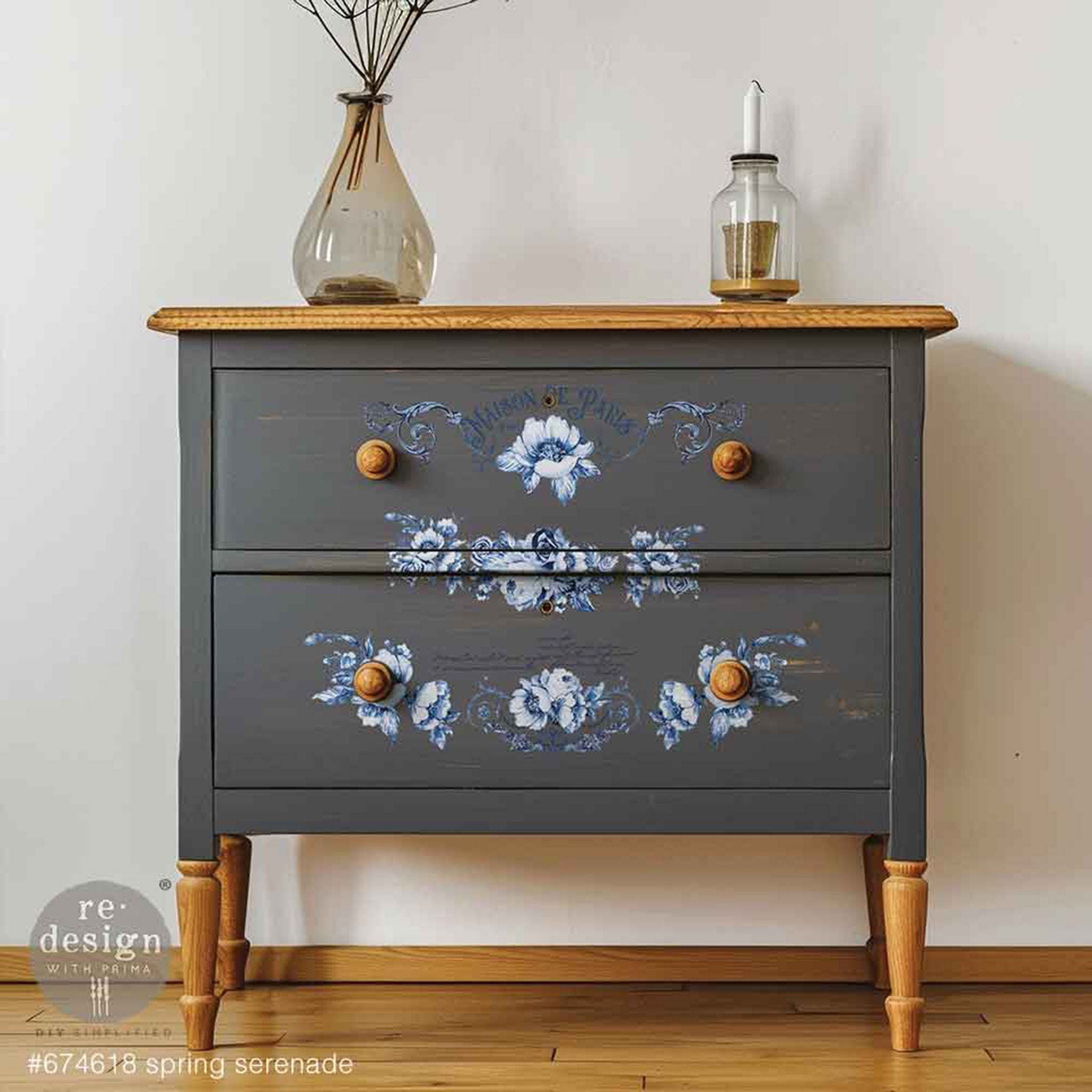 A 2-drawer nightstand is painted grey with natural wood accents and features ReDesign with Prima's Spring Serenade small rub-on transfers down the center of the drawers.