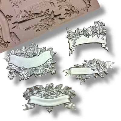 A silicone mold and silver colored castings featuring 4 unique banners surrounded by delicate flowers are against a white background.