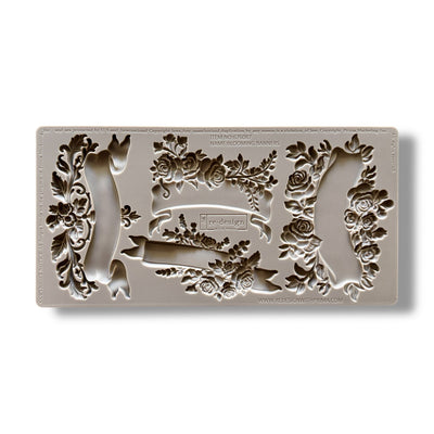 A silicone mold featuring 4 unique banners surrounded by delicate flowers is against a white background.
