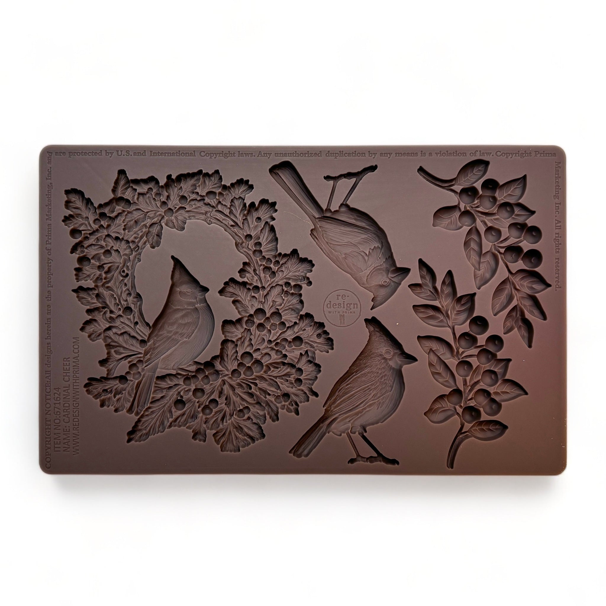 A brown silicone mold featuring a festive wreath with a resting cardinal, as well as two individual cardinals and two sprigs of greenery is against a white background.