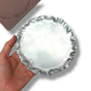 Hand holding a small silver dish on a white background