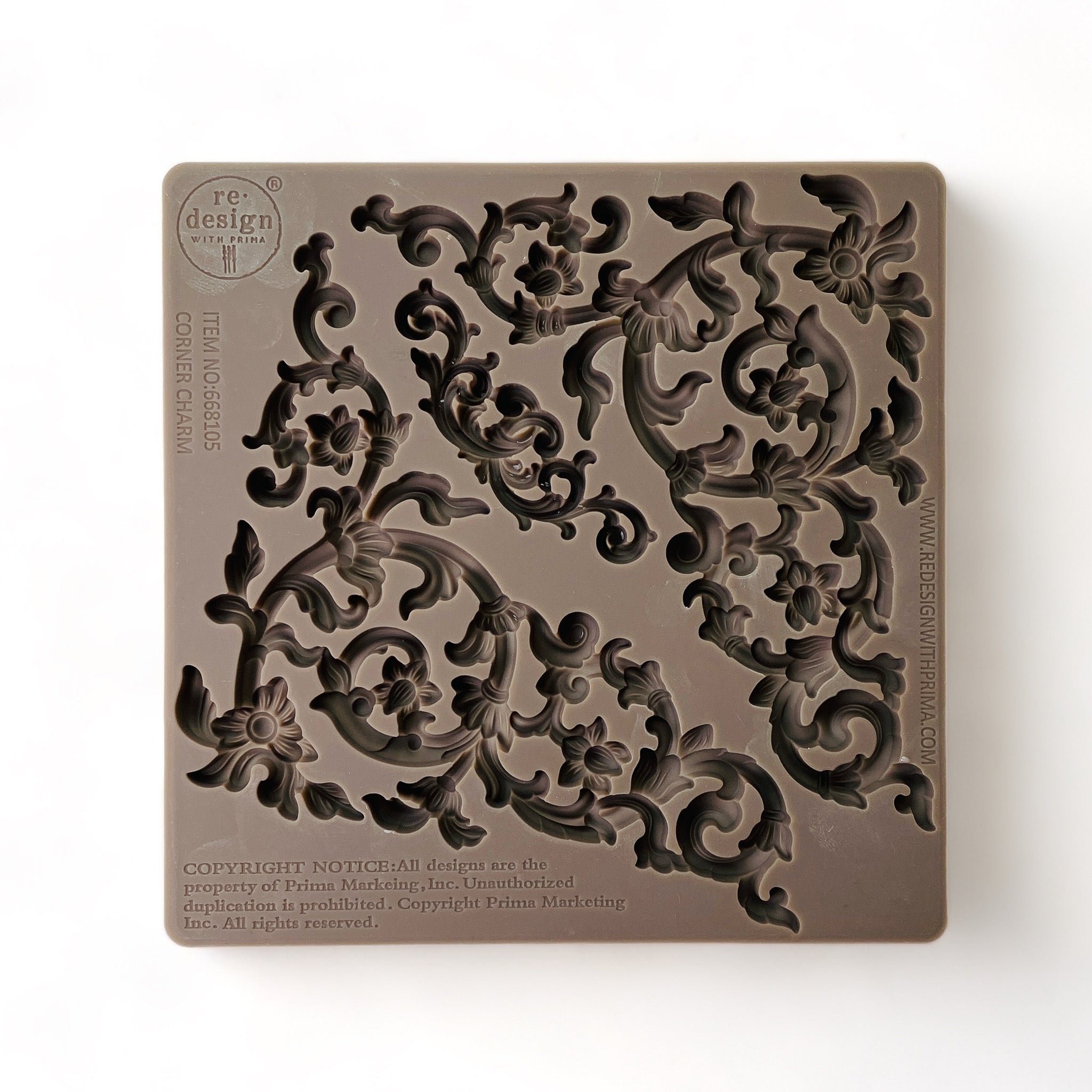 A brown silicone mold that features 2 scrolling vine corners and a small center accent scroll is against a white background.