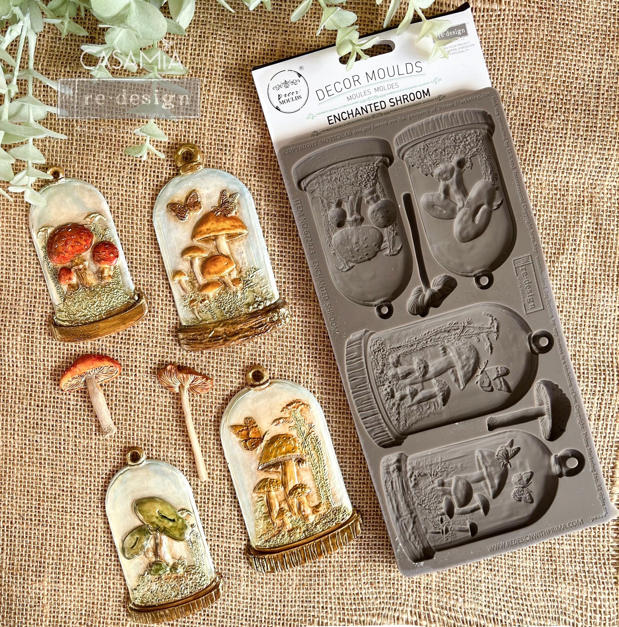 A package of ReDesign with Prima's Enchanted Shroom silicone mold and colorful castings created by Casamia are against a light brown burlap background.