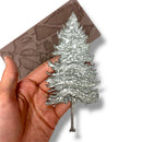 Silver tree-shaped object held in a hand with a brown silicone mold in the background
